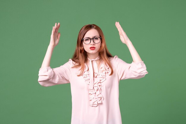 Vue de face enseignante en chemisier rose sur fond vert collège couleur livre de travail étudiant emploi bibliothèque jeune femme de l'école