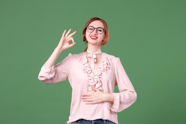 Vue de face enseignante en chemisier rose sur fond vert étudiant bibliothèque de l'école jeune travail collège leçon livre de couleur femme travail