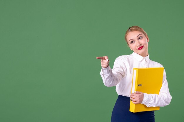 Vue de face enseignante tenant des fichiers jaunes et pointant sur le vert