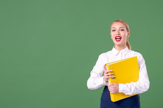 Photo gratuite vue de face enseignante tenant des fichiers jaunes sur vert