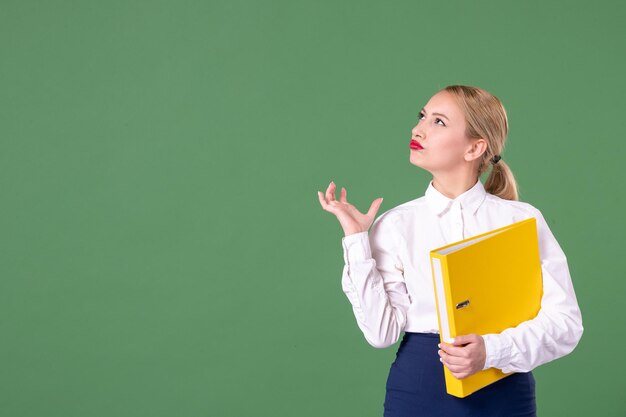 Vue de face enseignante tenant des fichiers jaunes sur vert