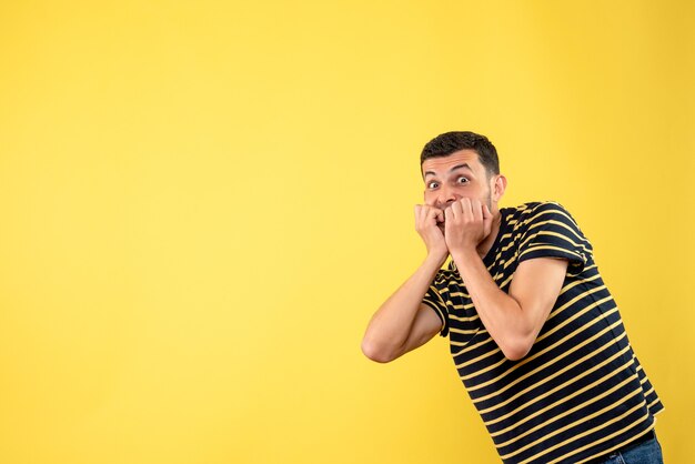 Vue de face étonné bel homme en t-shirt rayé noir et blanc fond isolé jaune