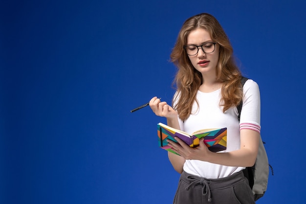 Vue de face de l'étudiante en chemise blanche tenant un stylo et un cahier