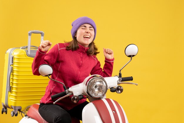 Vue de face exaltée jeune femme dans des vêtements décontractés sur cyclomoteur