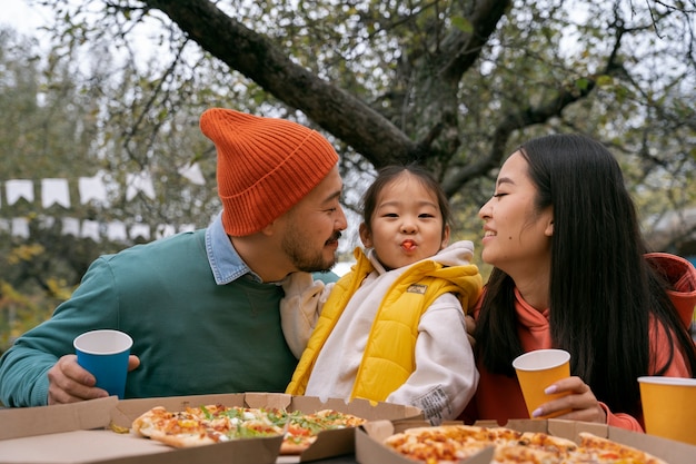 Vue de face famille mangeant de la pizza à l'extérieur