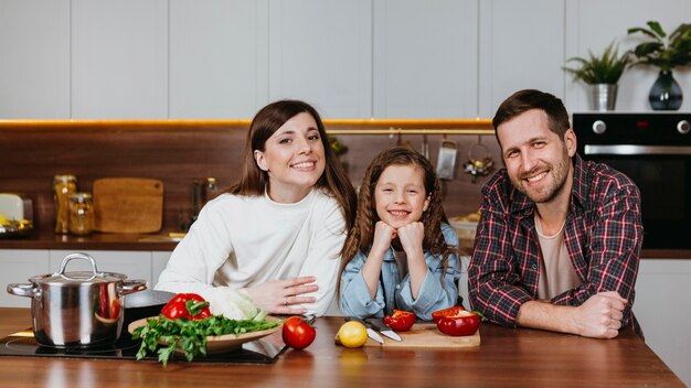 Vue de face de la famille posant dans la cuisine