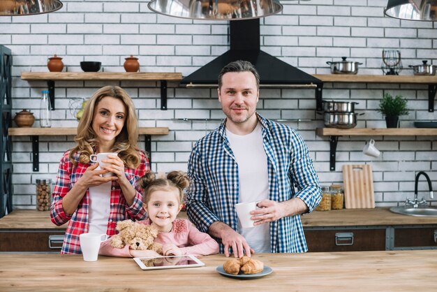 Vue de face de la famille souriante prenant son petit déjeuner dans la cuisine