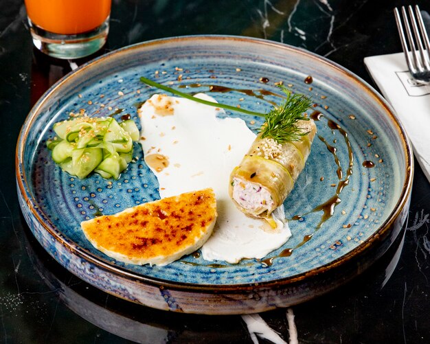 Vue de face farcie de courgettes avec une tranche de fromage et de concombre sur une plaque bleue