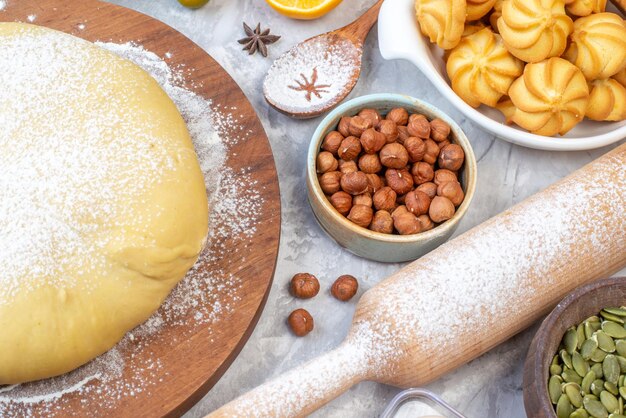 Vue de face de la farine de pâtisserie crue sur une râpe à biscuits aux noisettes en bois rond sur fond gris