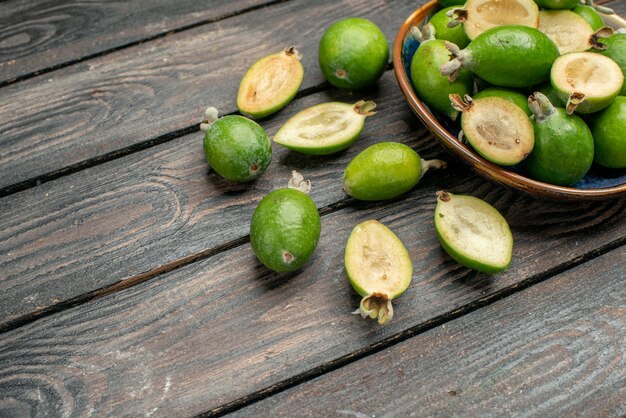 Vue de face des feijoas verts frais à l'intérieur de la plaque sur un bureau rustique en bois photo couleur fruits jus aigre mûr