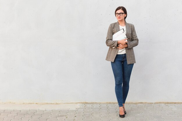 Vue de face de la femme d'affaires posant avec le bloc-notes à l'extérieur