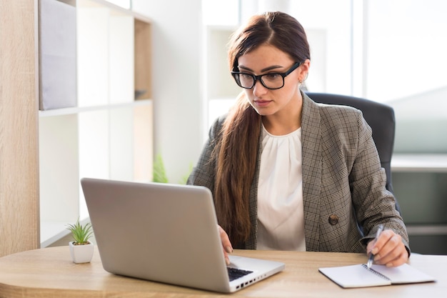 Vue de face de la femme d'affaires travaillant sur un ordinateur portable au bureau