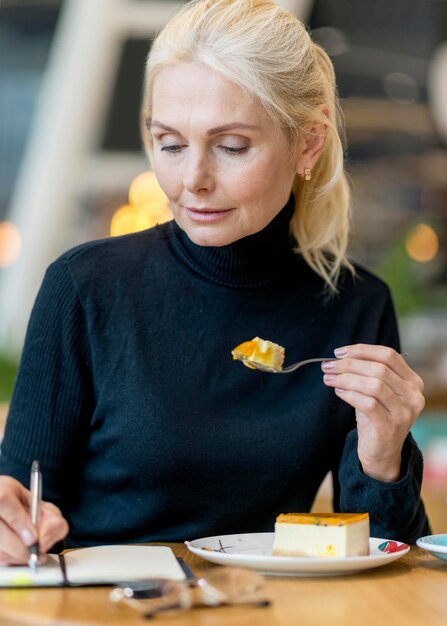 Vue de face d'une femme âgée ayant un dessert tout en travaillant