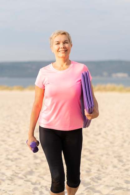 Photo gratuite vue de face d'une femme âgée avec des équipements de travail sur la plage