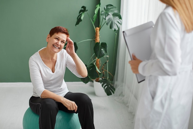 Vue de face de la femme âgée smiley dans la récupération de covid faisant des exercices physiques