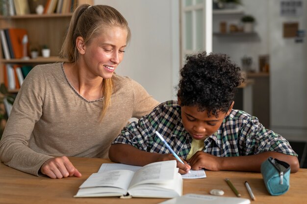 Vue de face femme aidant un enfant à faire ses devoirs