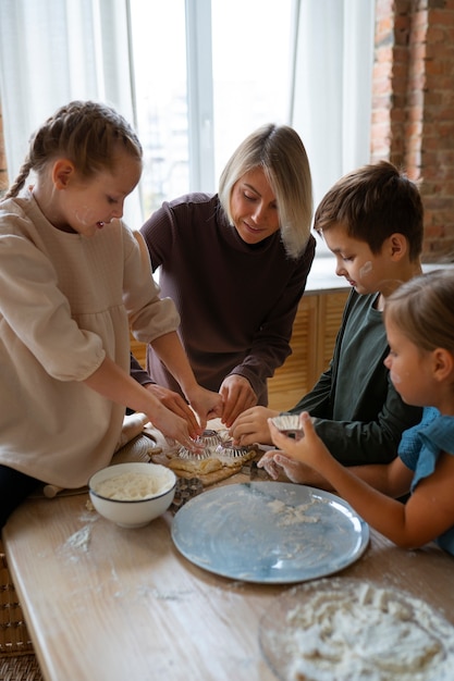 Photo gratuite vue de face femme aidant les enfants à cuisiner