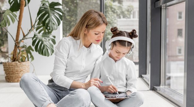 Vue de face femme aidant sa fille à faire leurs devoirs