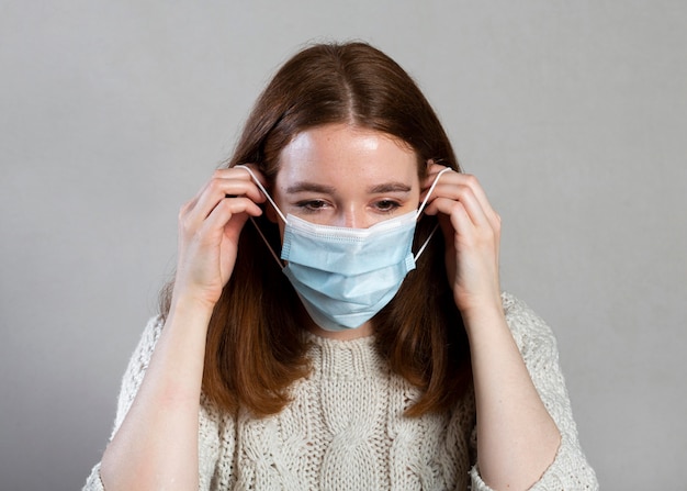 Vue de face de la femme à l'aide d'un masque médical pour la protection