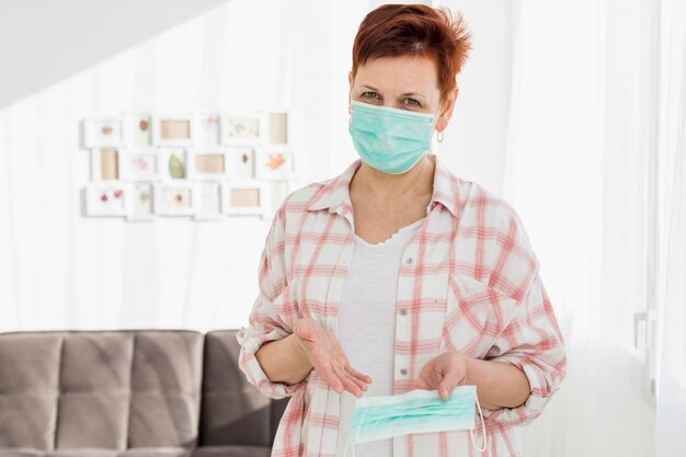 Vue de face d'une femme aînée avec un masque médical en montrant une autre qu'elle tient