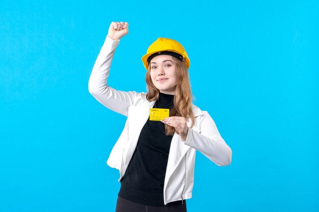 Vue de face femme architecte tenant une carte bancaire sur bleu