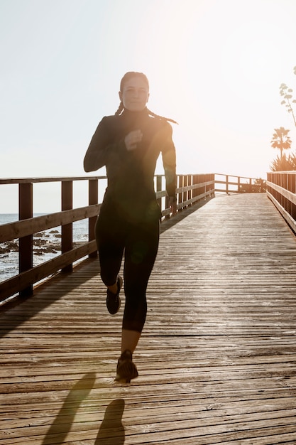Vue de face de la femme athlétique jogging au bord de la plage avec espace copie