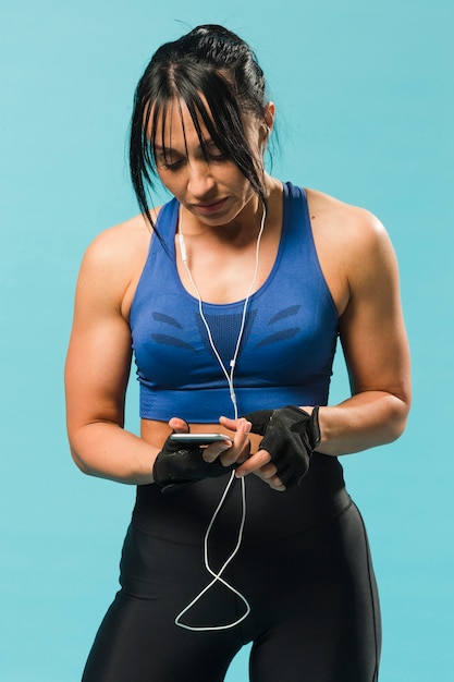 Photo gratuite vue de face de femme athlétique en tenue de gym avec smartphone