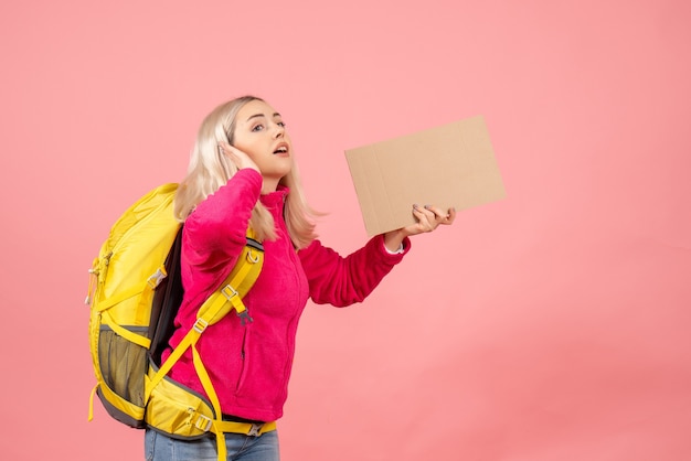 Photo gratuite vue de face femme blonde voyageur avec sac à dos tenant carton