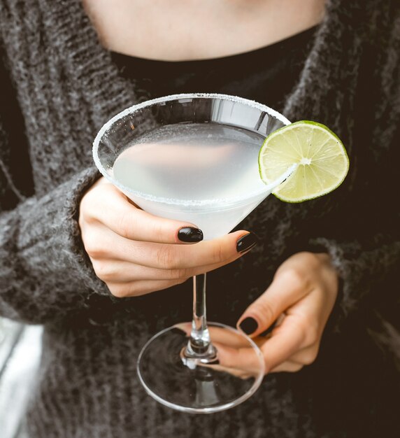 Vue de face une femme boit un cocktail rafraîchissant avec une tranche de citron vert