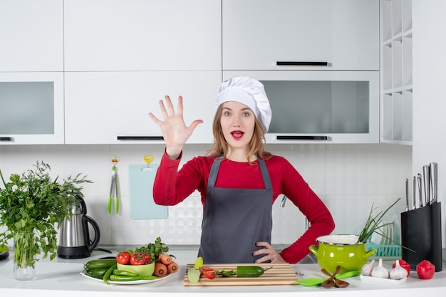 Vue de face femme chef en chapeau de cuisinier donnant cinq