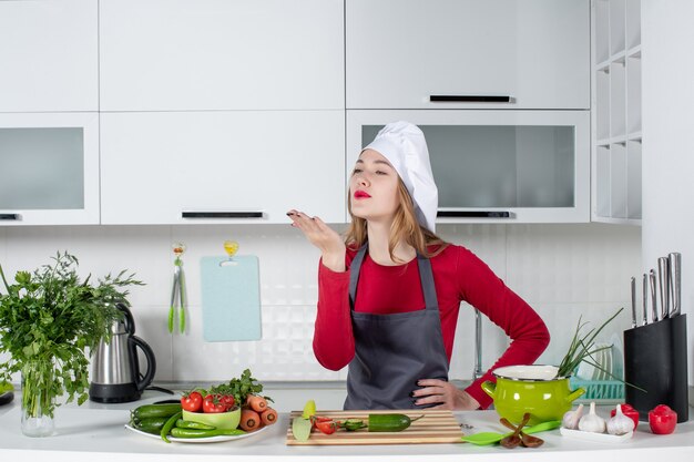 Vue de face femme chef en chapeau de cuisinier soufflant baiser