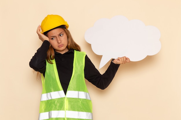 Photo gratuite vue de face femme constructeur en casque jaune tenant une pancarte blanche en pensant stressant sur blanc femme de bureau