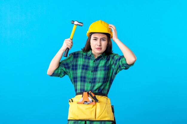 Vue de face femme constructeur en uniforme tenant un marteau sur bleu