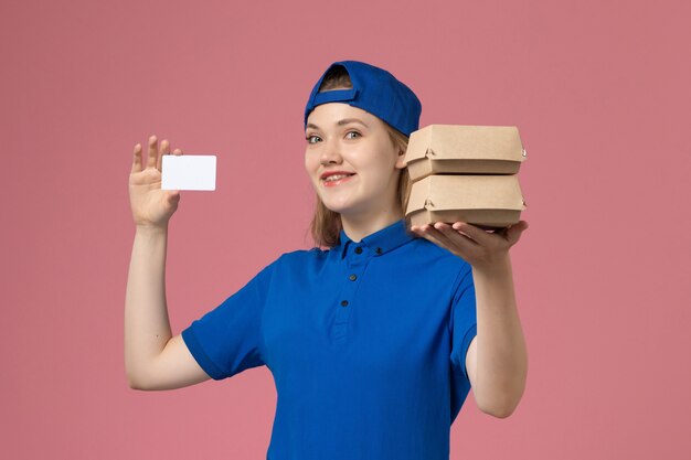 Vue de face femme courrier en cape uniforme bleu tenant peu de colis de nourriture de livraison et carte sur fond rose employé de livraison de services