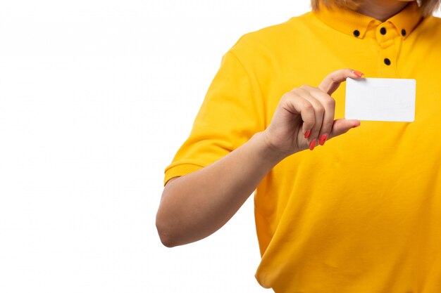 Une vue de face femme courrier en chemise jaune casquette jaune et jean noir tenant une carte blanche sur blanc