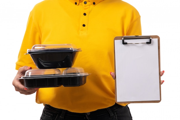 Une vue de face femme courrier en chemise jaune casquette jaune jeans noirs tenant des bols avec du papier alimentaire sur blanc