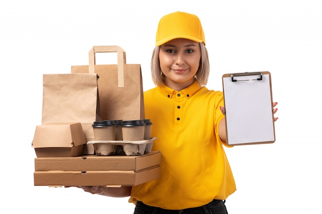 Une vue de face femme courrier en chemise jaune casquette jaune jeans noirs tenant des paquets et des boîtes souriant sur blanc