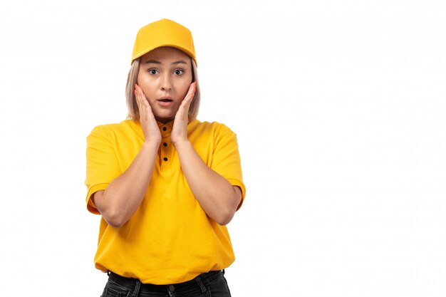 Une vue de face femme courrier en chemise jaune et casquette jaune surpris posant sur blanc