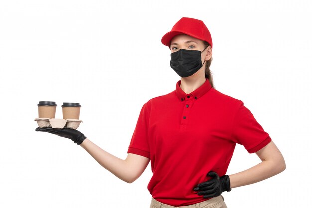 Une vue de face femme courrier en chemise rouge bonnet rouge gants noirs et masque noir tenant du café