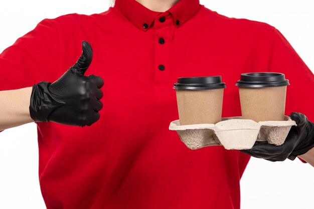 Une vue de face femme courrier en chemise rouge gants noirs tenant du café sur blanc