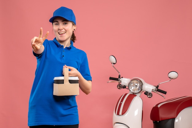 Vue de face femme courrier avec livraison de café sur le service de livraison de travail rose travail travailleur femme vélo uniforme