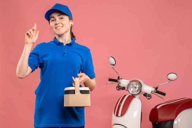 Vue de face femme courrier avec livraison de café sur l'uniforme de livraison de travail rose service travail femme vélo