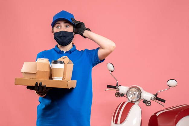 Vue de face femme courrier en masque avec livraison de café et de nourriture sur le rose