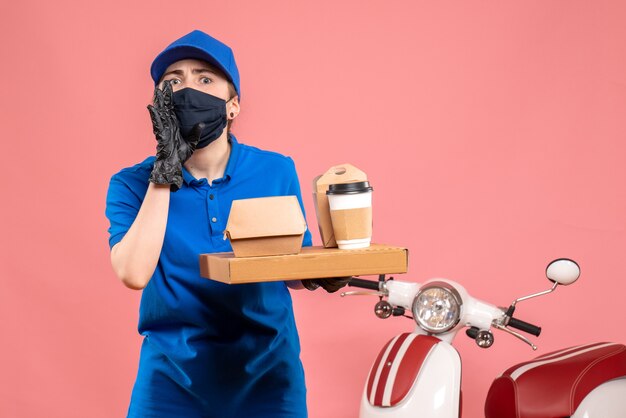 Vue de face femme courrier en masque avec livraison de café et de nourriture sur le rose