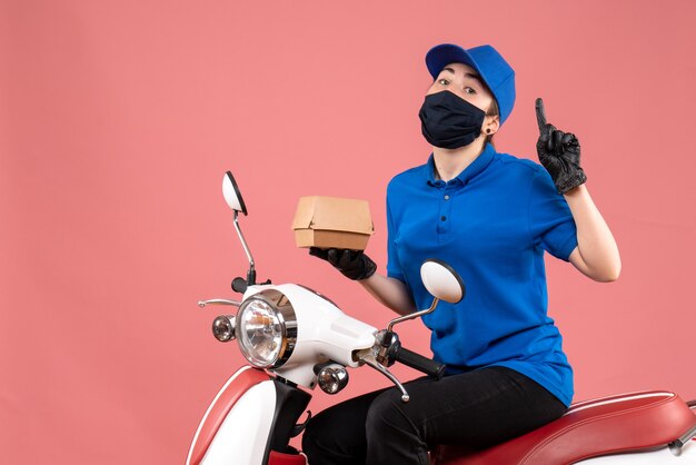 Vue de face femme courrier en masque avec petit paquet de nourriture sur le rose