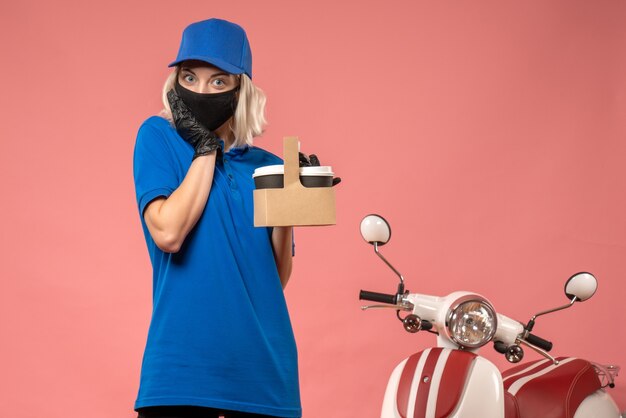 Vue de face femme courrier en masque avec des tasses à café sur le rose