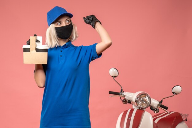 Vue de face femme courrier en masque avec des tasses à café sur le rose