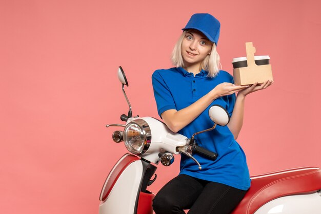 Vue de face femme courrier avec des tasses à café sur le service de livraison rose travail travail uniforme de couleur