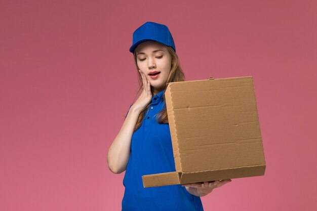 Vue de face femme courrier en uniforme bleu tenant la boîte de livraison de nourriture l'ouvrir sur fond rose entreprise uniforme de service d'emploi