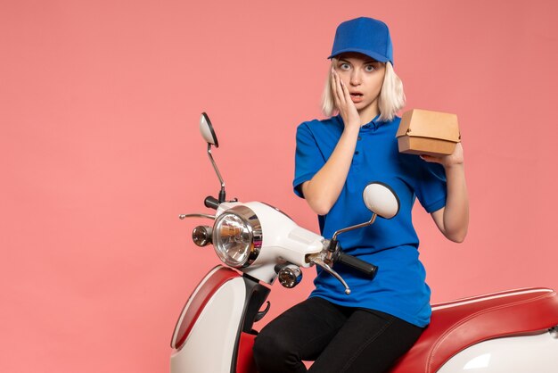 Vue de face femme courrier sur vélo avec petit paquet de nourriture sur le rose